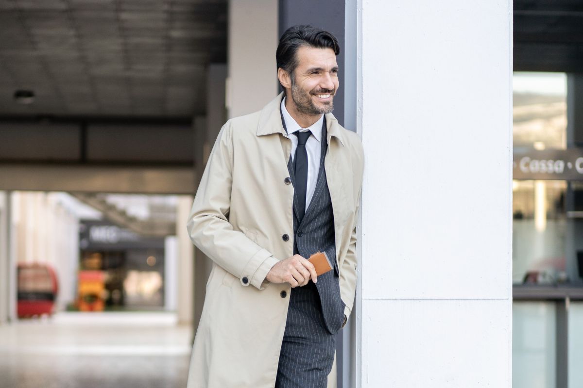 Uomo sorridente vestito elegante con un mini portafoglio in mano
